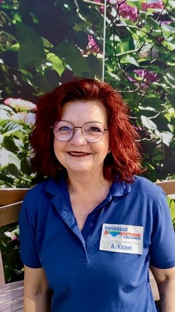 Eine Frau mit roten Haaren und Brille sitzt auf einer Bank.