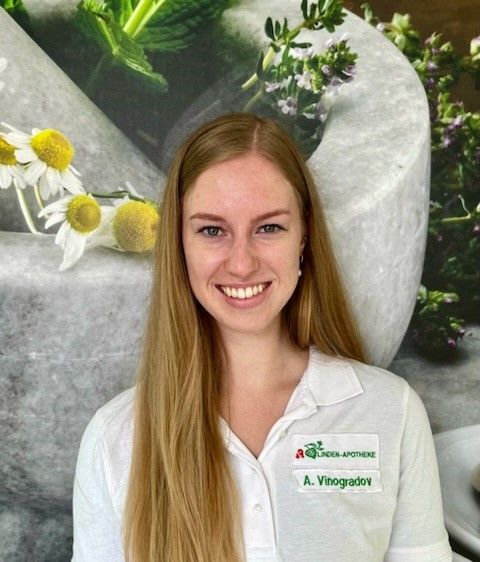 Eine Frau in einem weißen Hemd lächelt vor einem Blumenbild.