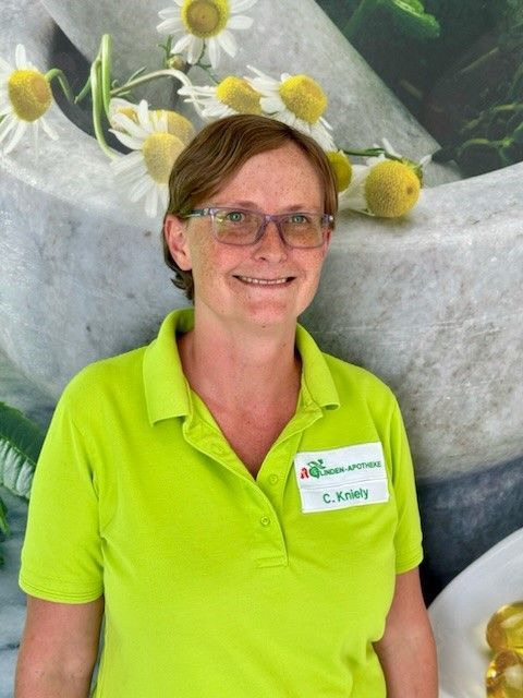 Eine Frau mit Brille und grünem Hemd lächelt