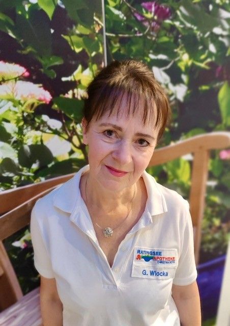 Eine Frau in einem weißen Hemd sitzt auf einer Bank.