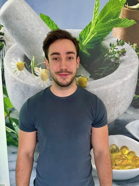 Ein Mann mit Bart steht vor einem Mörser und einer Schüssel mit Pillen.