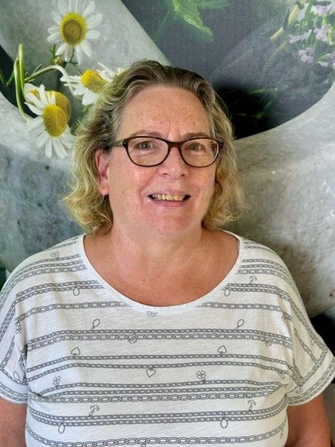 Eine Frau mit Brille und weißem Hemd lächelt