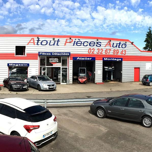 Façade d'un magasin de pièces automobiles avec des voitures garées sous un ciel bleu