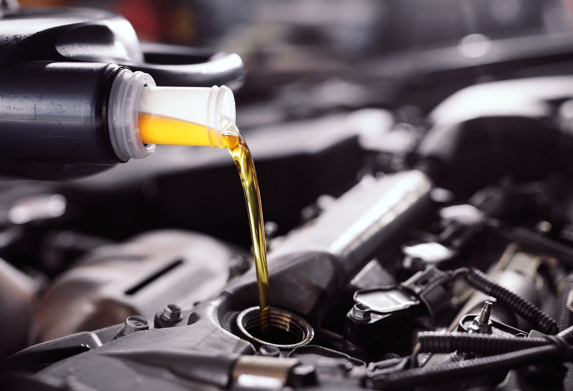De l'huile moteur se déverse d'une bouteille dans le moteur d'une voiture lors de l'entretien.