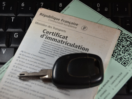 Certificat d’immatriculation et clé de véhicule posés sur une surface.