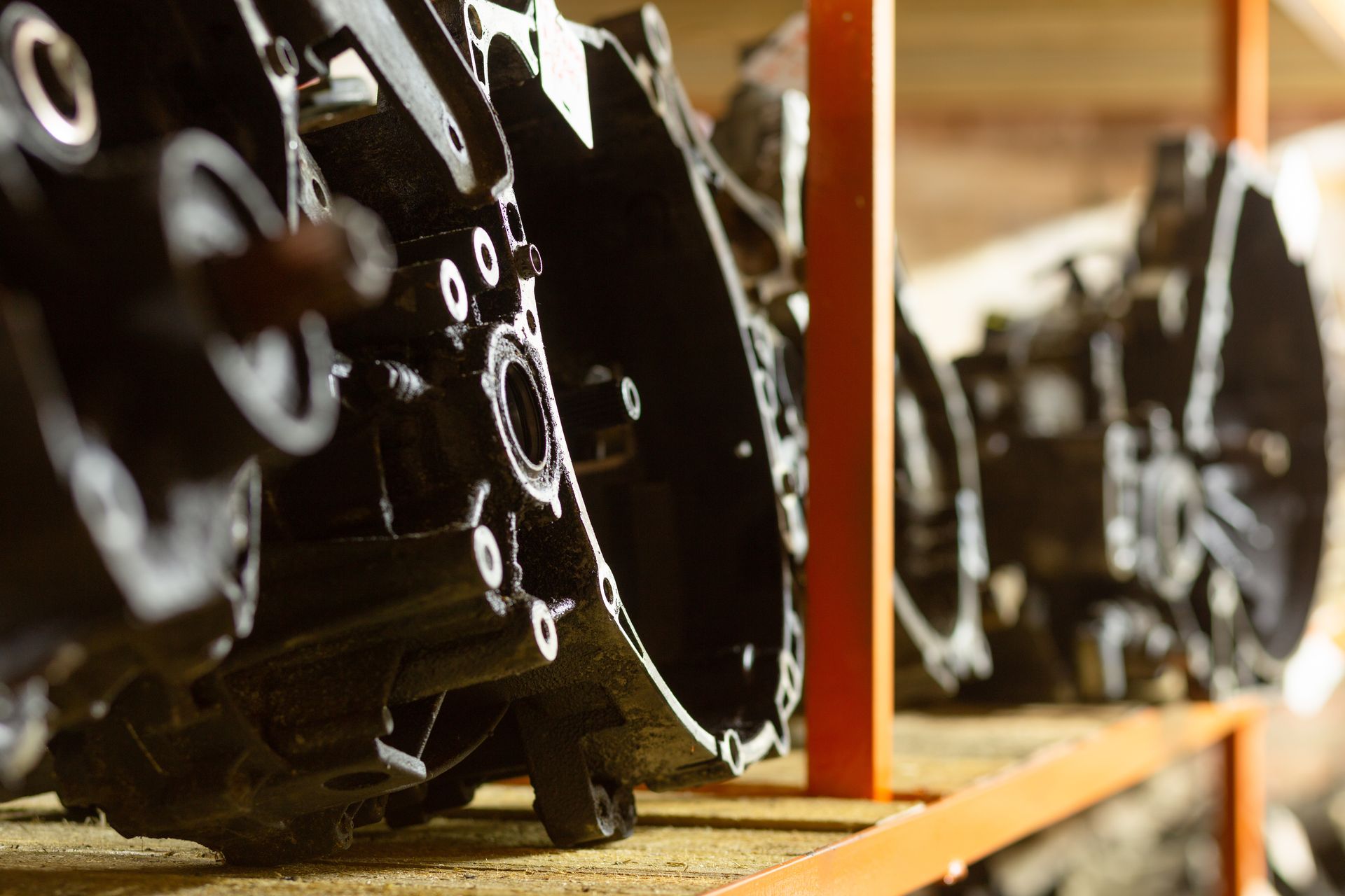 Roues ou engrenages en métal noir sur un convoyeur d'usine, avec un rail orange au premier plan.