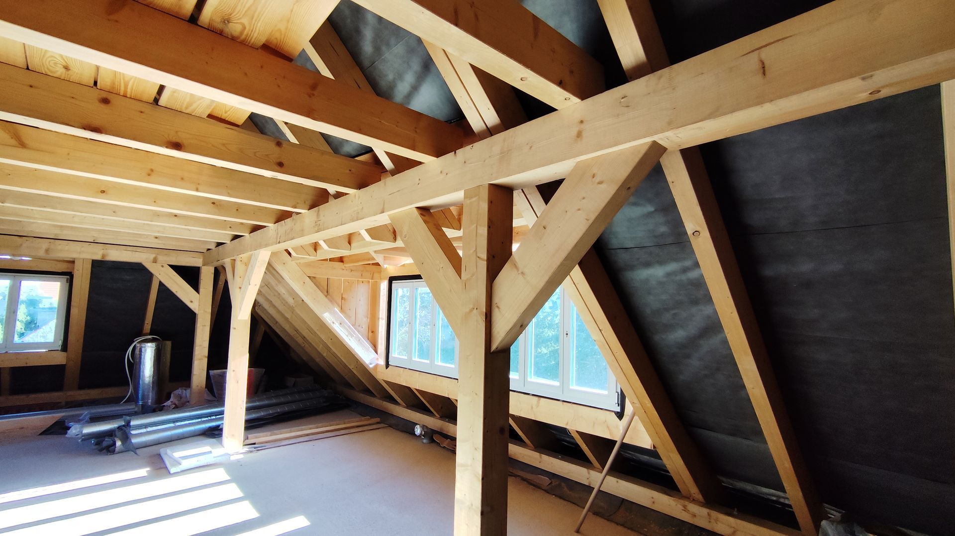 Interno della mansarda con travi in ​​legno a vista e lucernari in fase di costruzione