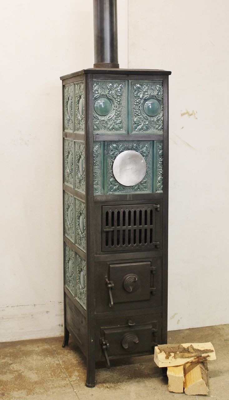 Kachelofen Nr. 1936- Gestellkachelofen aus regionaler Produktion mit petrolfarbenen Kacheln welche mit einem Rebenmotiv verziert sind