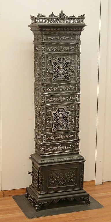 Poêle en fonte n° 1175 – Perler Ofen / Poêle en fonte impérial et royal «Kastell-Frühstücksofen», vers 1880, avec allumage sur le côté gauche (également possible sur le côté droit), la partie centrale et attrayante du poêle est occupée par les portes ajourées du compartiment de chauffage qui arbore un motif de femme fortement accentué et très finement travaillé.