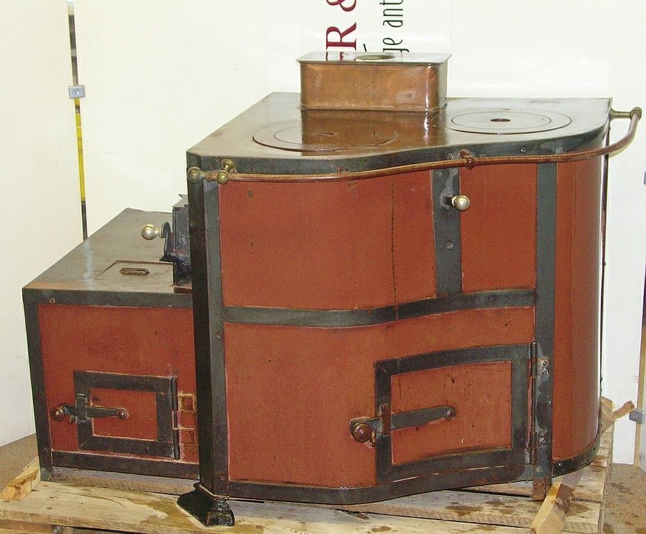 Cucina rustica n. 1390 - Perler Ofen/Cucina curva risalente al 1900 circa con aggiunta (ceneraio) sul lato sinistro, focolare e forno sul lato sinistro, con 2 piastre di cottura e vasca per l’acqua in rame, nonché ampio vano portaoggetti.