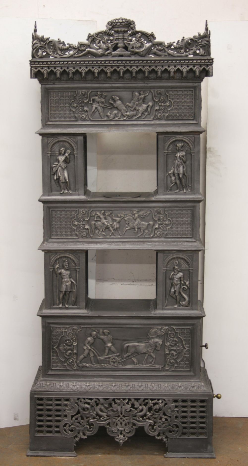 Poêle en fonte n° 752, richement décoré de motifs de la mythologie grecque, de scènes de chasse et de récolte.