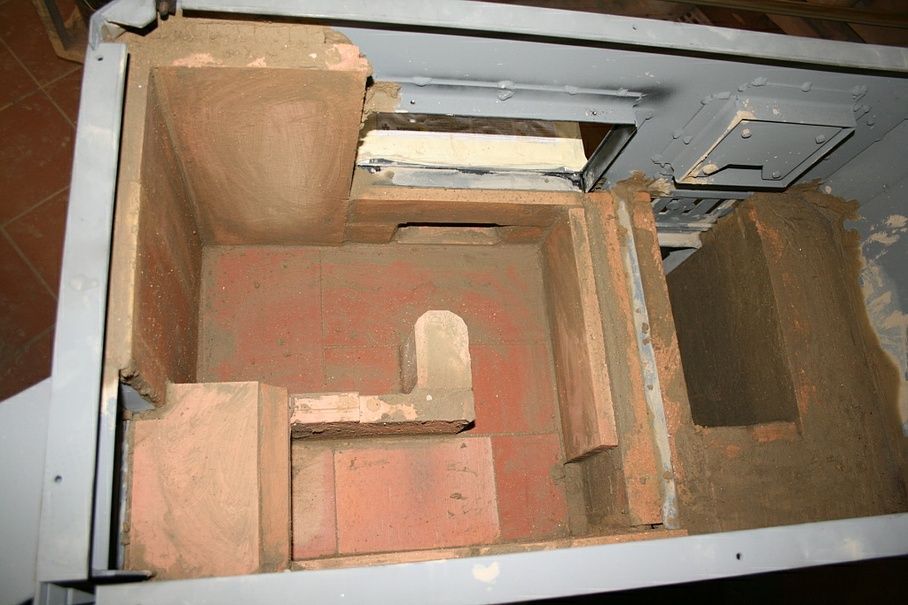 Pose de pierres réfractaires sur un fourneau à bois avec four à chaleur inférieure