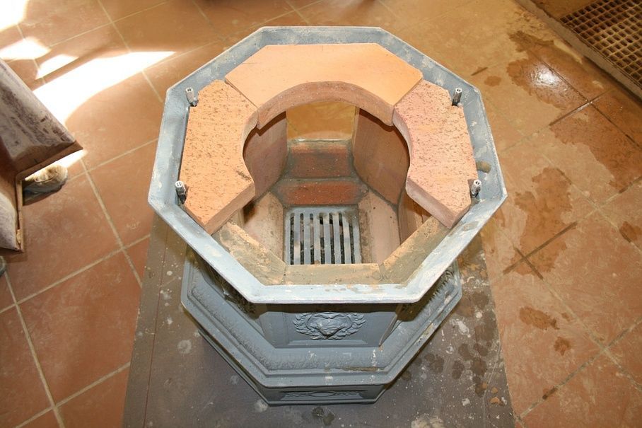 Pose de pierres réfractaires sur un poêle en fonte