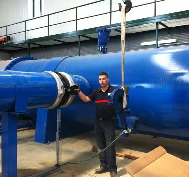 Un hombre está de pie junto a una gran tubería azul.