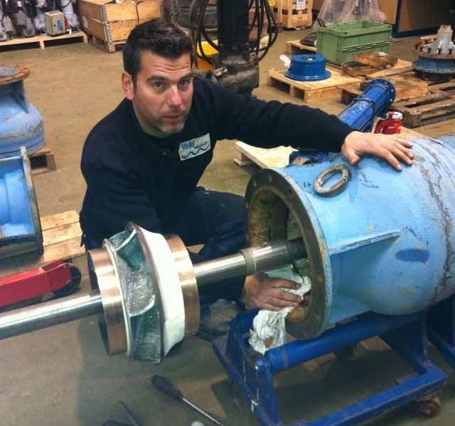 Un hombre está arrodillado junto a un gran objeto azul.