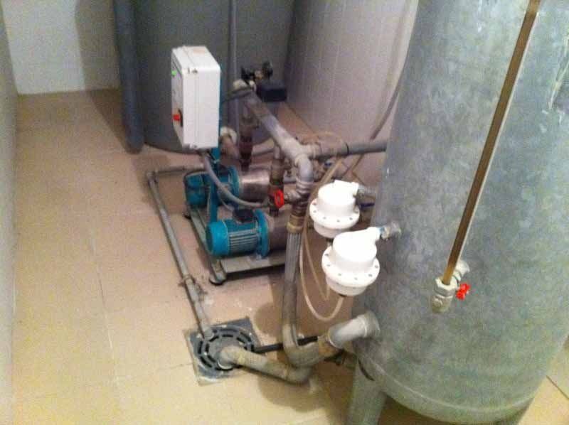 Una habitación con un tanque de agua y una bomba en el piso.