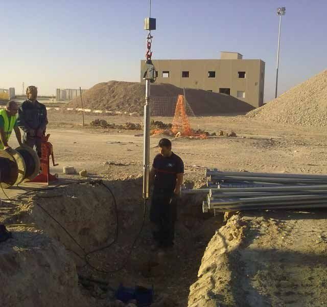 Un hombre con una camisa negra está parado en un agujero en la tierra.