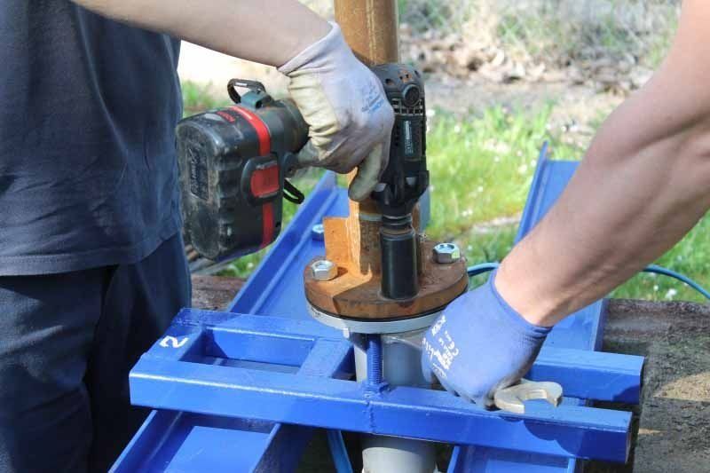 Un hombre está usando un taladro para hacer un agujero en una tubería.