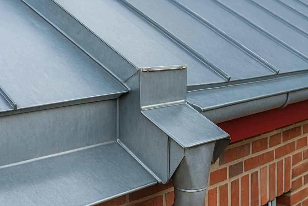 Eine Dachrinne an der Seite eines Backsteingebäudes mit einem Metalldach