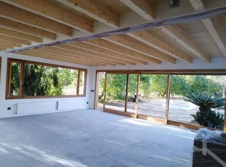 Una habitación vacía con techo de madera y muchas ventanas.
