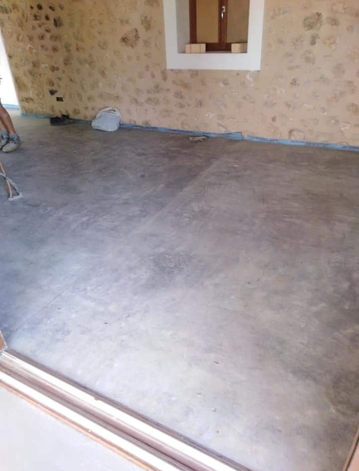 Una persona está aspirando un piso de concreto en una habitación.