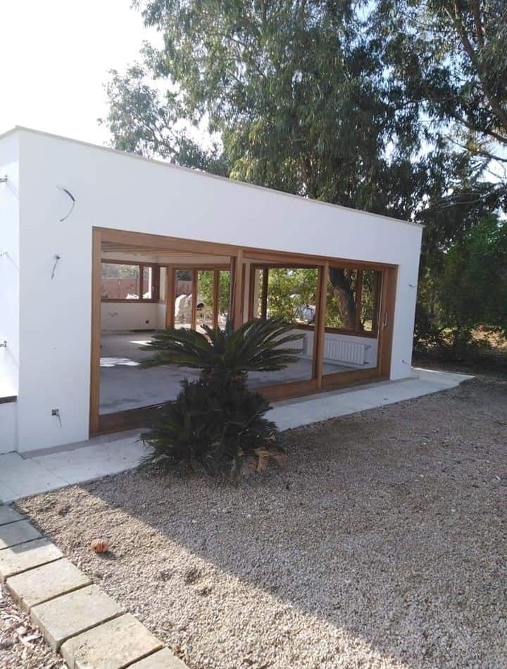 Un edificio blanco con muchas ventanas y árboles al fondo.