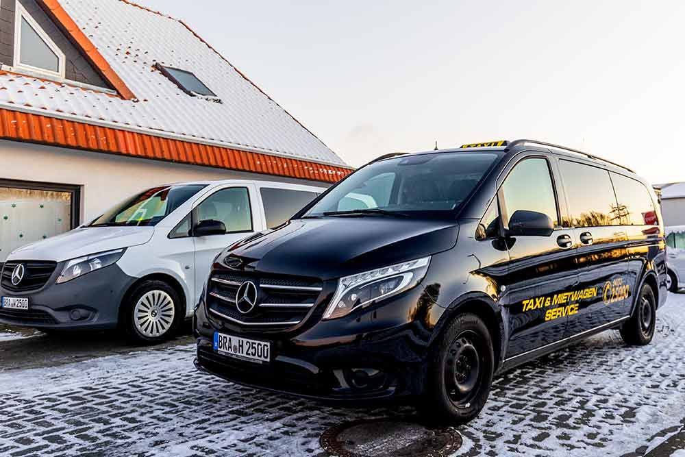 zwei schwarze und weiße mercedes-vans stehen vor einem schneebedeckten haus .
