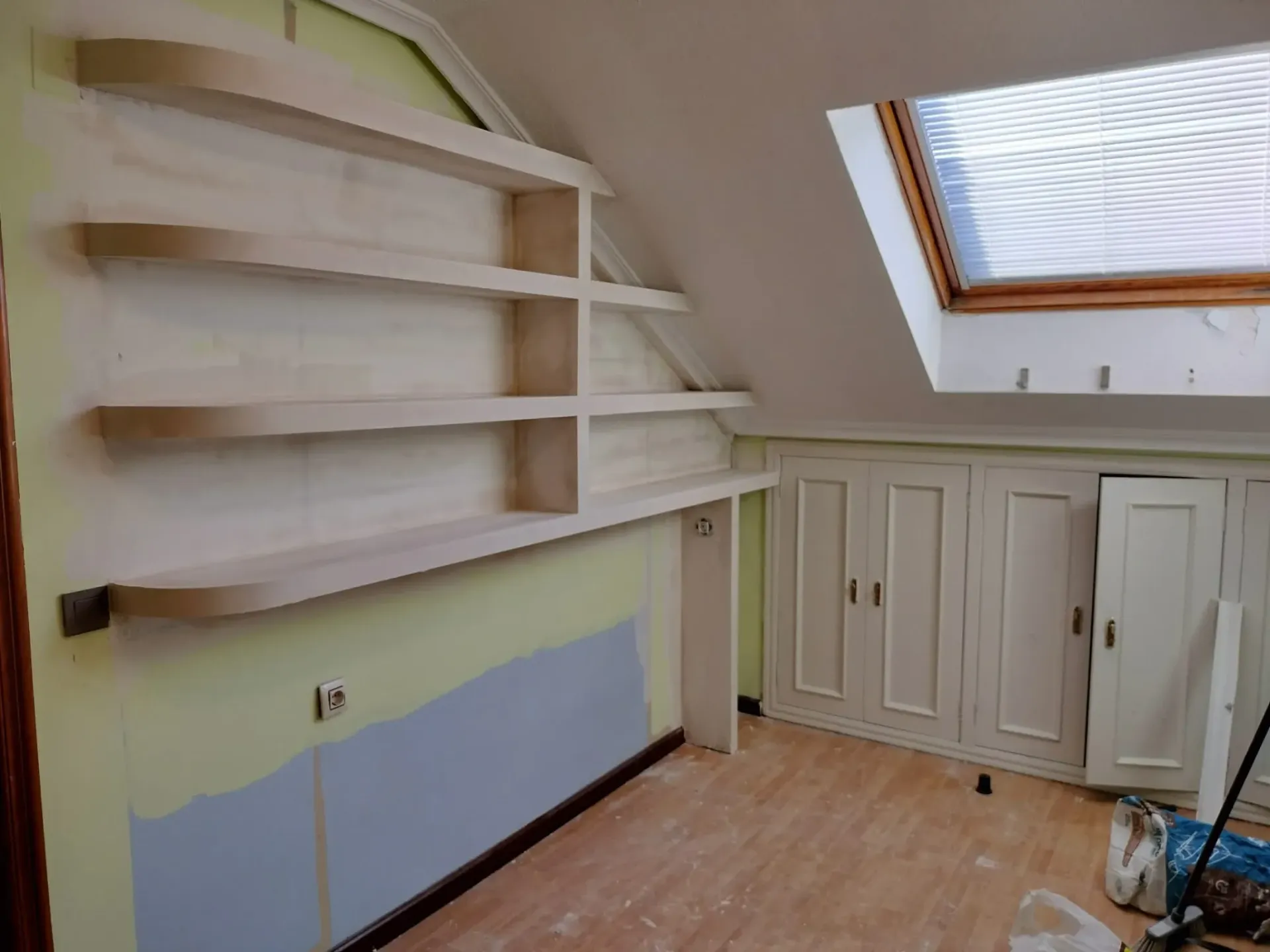 Estanterías de madera sin acabado en una pared verde pálida