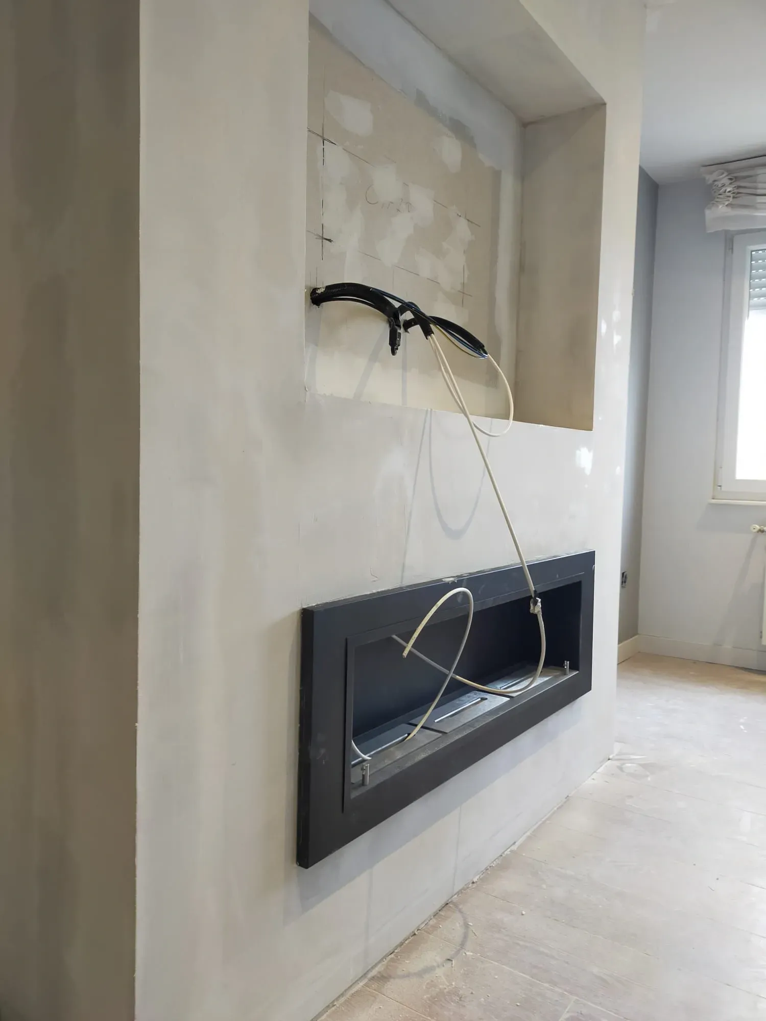 Una chimenea eléctrica lineal de color negro instalada en una pared de color claro