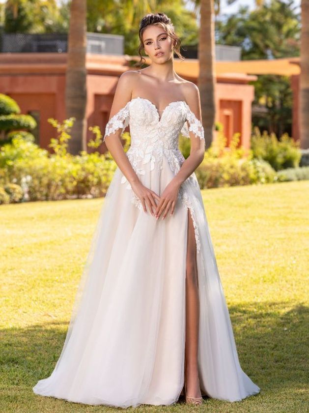Eine Frau trägt ein weißes Hochzeitskleid mit hohem Schlitz.