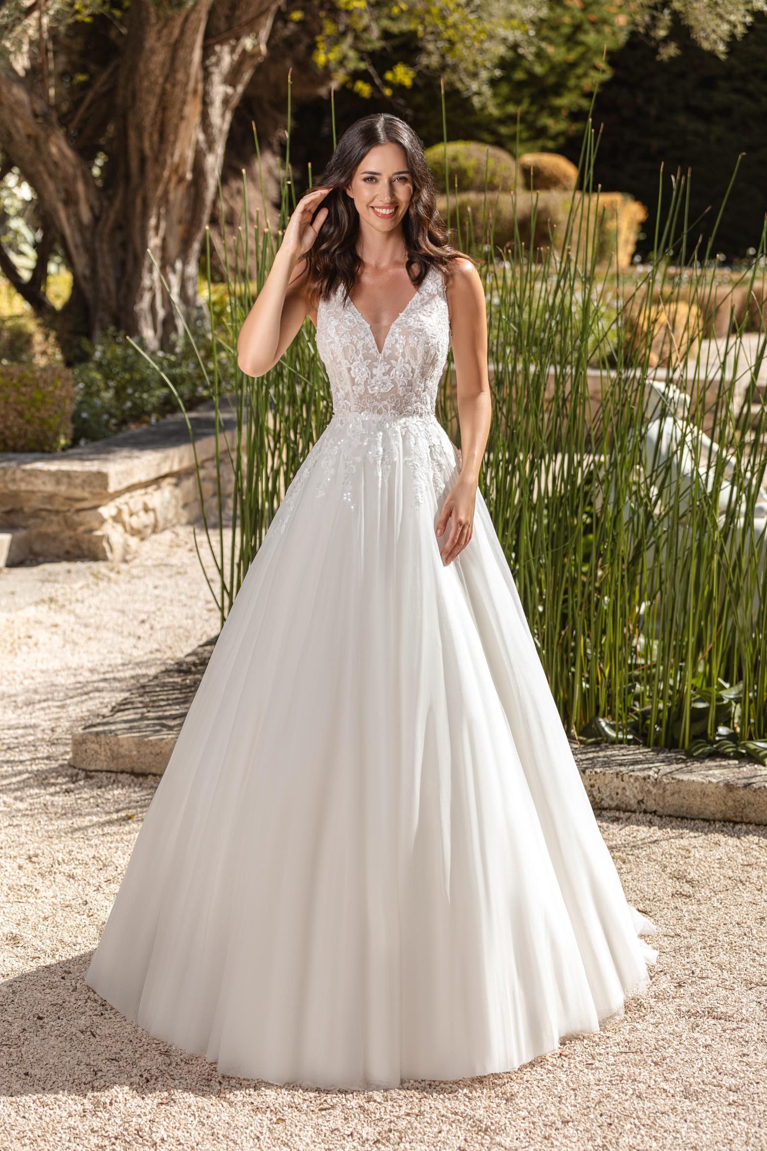 Eine Frau in einem weißen Hochzeitskleid steht neben einem Pool.