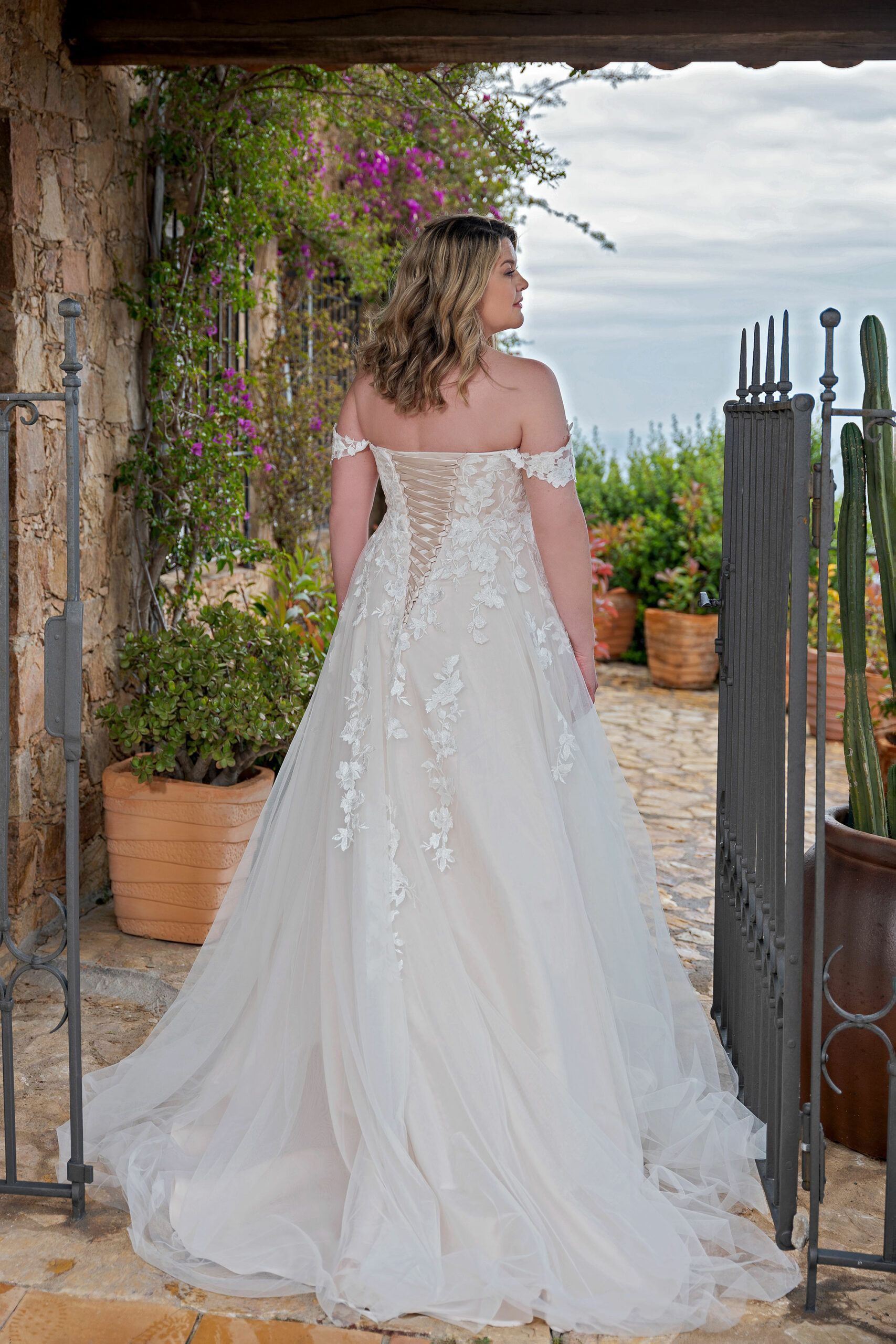 Eine Frau in einem Brautkleid steht vor einem Tor.