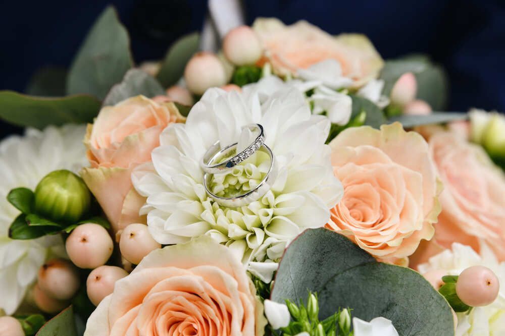Die Eheringe liegen auf einem Blumenstrauß.