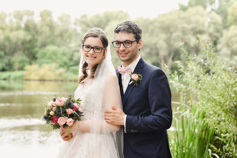 Eine Braut und ein Bräutigam posieren für ein Foto vor einem See.