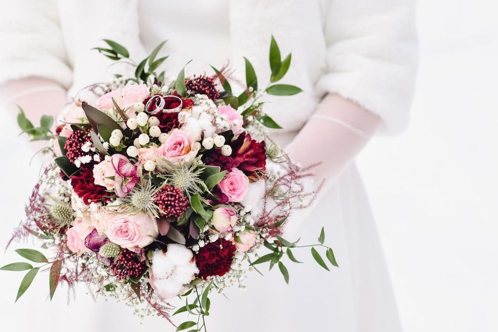 Eine Braut in einem weißen Kleid hält einen Blumenstrauß.