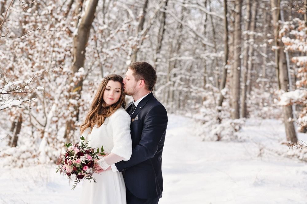 Eine Braut und ein Bräutigam küssen sich im Schnee.