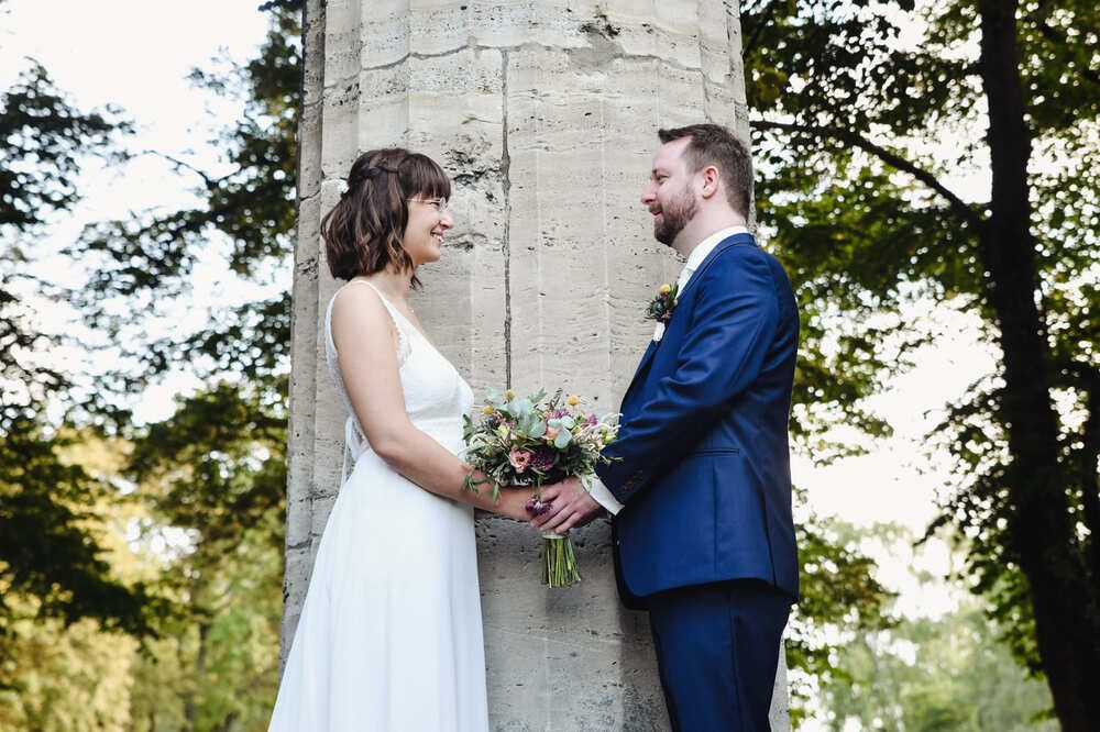 Eine Braut und ein Bräutigam stehen nebeneinander und halten Händchen.