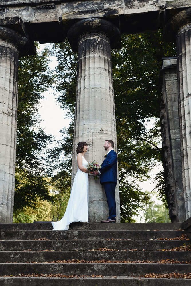 Braut und Bräutigam stehen nebeneinander vor einer Säule.