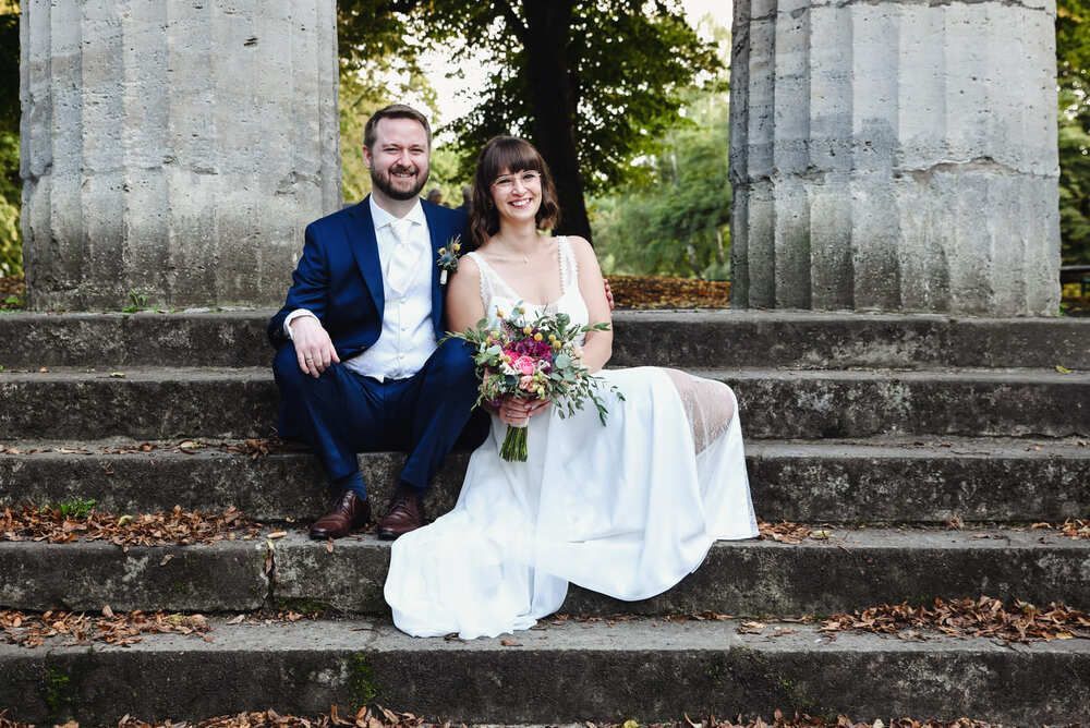 Eine Braut und ein Bräutigam sitzen auf den Stufen eines Gebäudes.