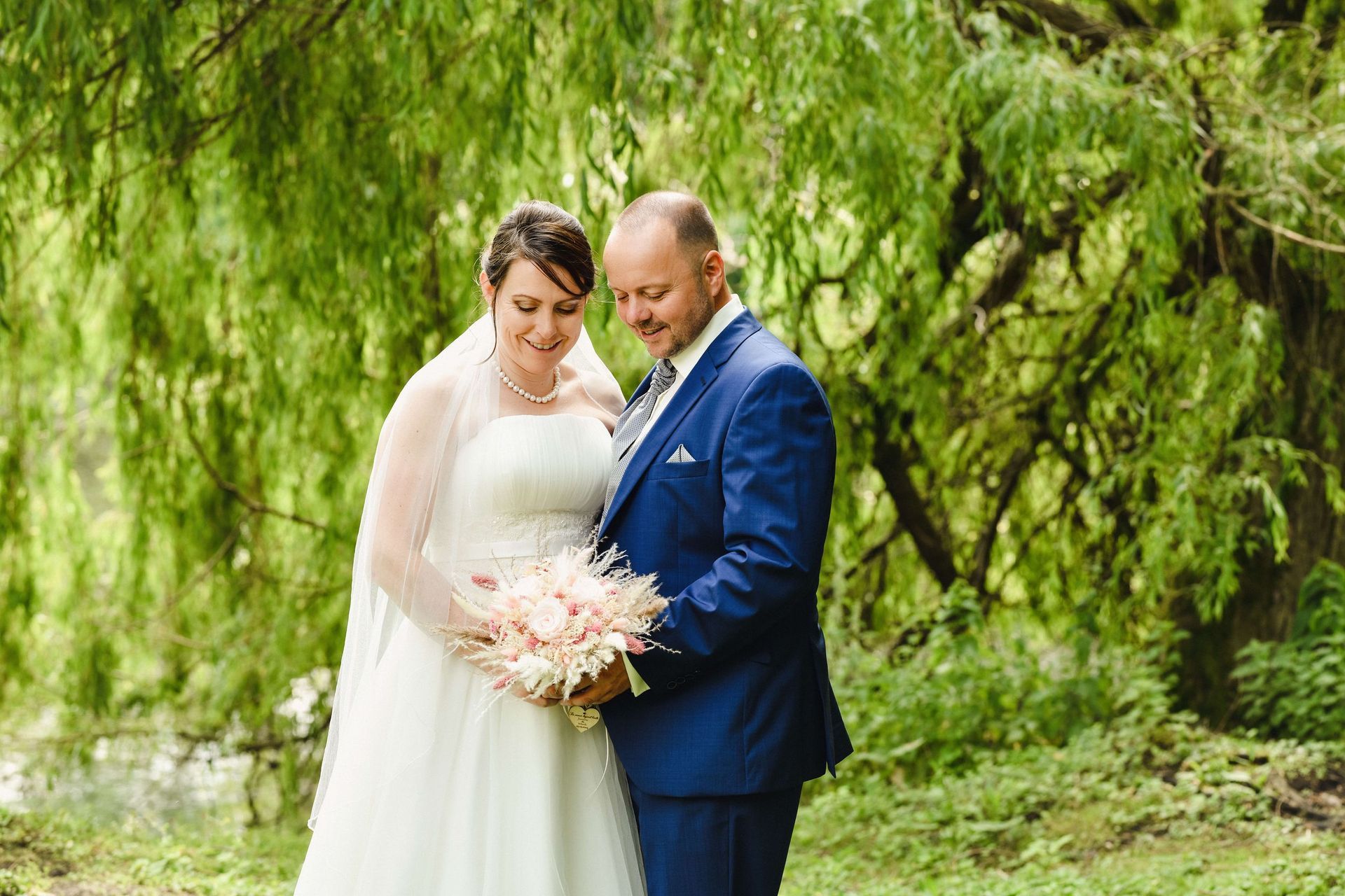 Eine Braut und ein Bräutigam posieren für ein Foto vor einem Baum.