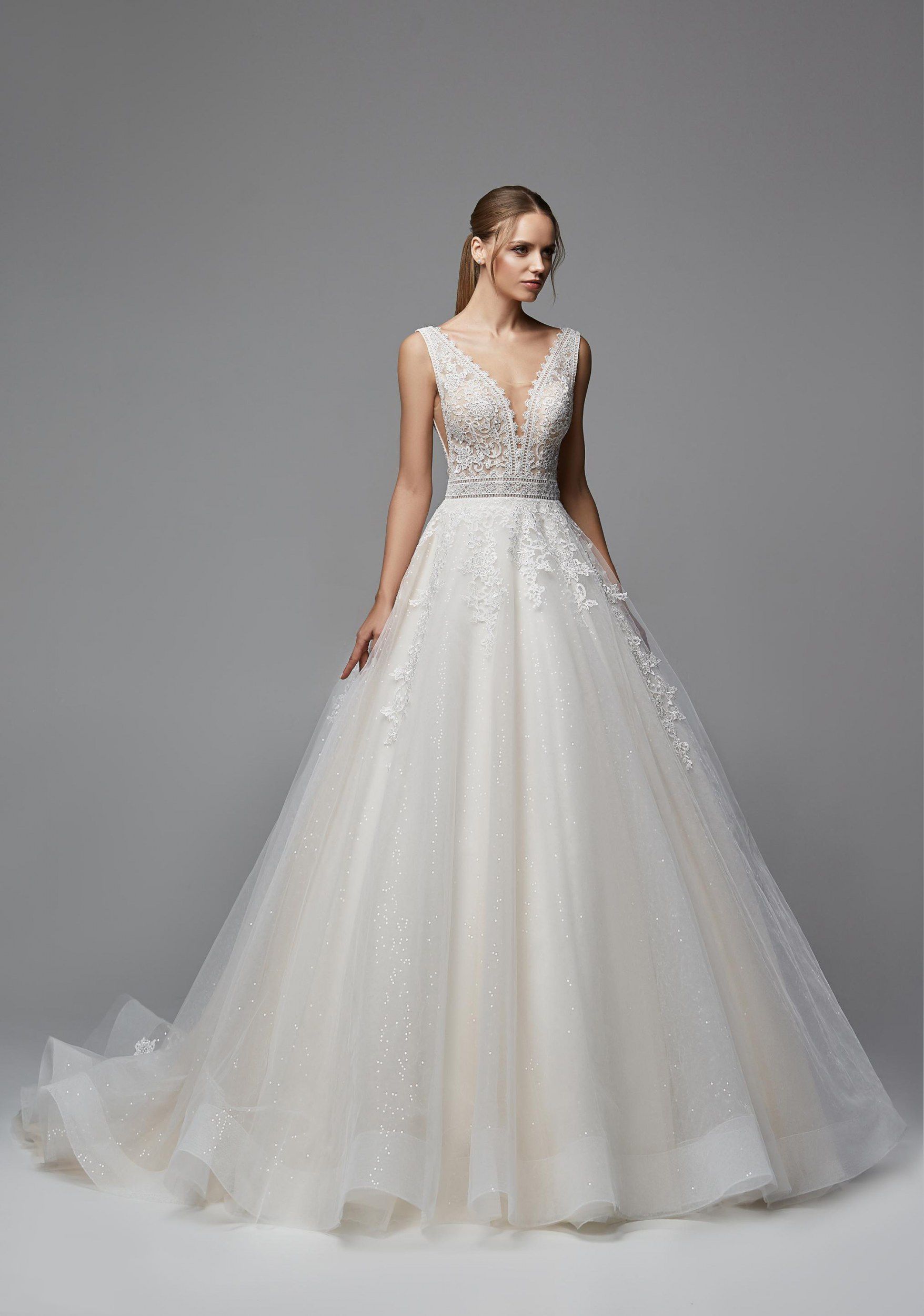 Eine Frau in einem weißen Hochzeitskleid steht vor einem weißen Gebäude.