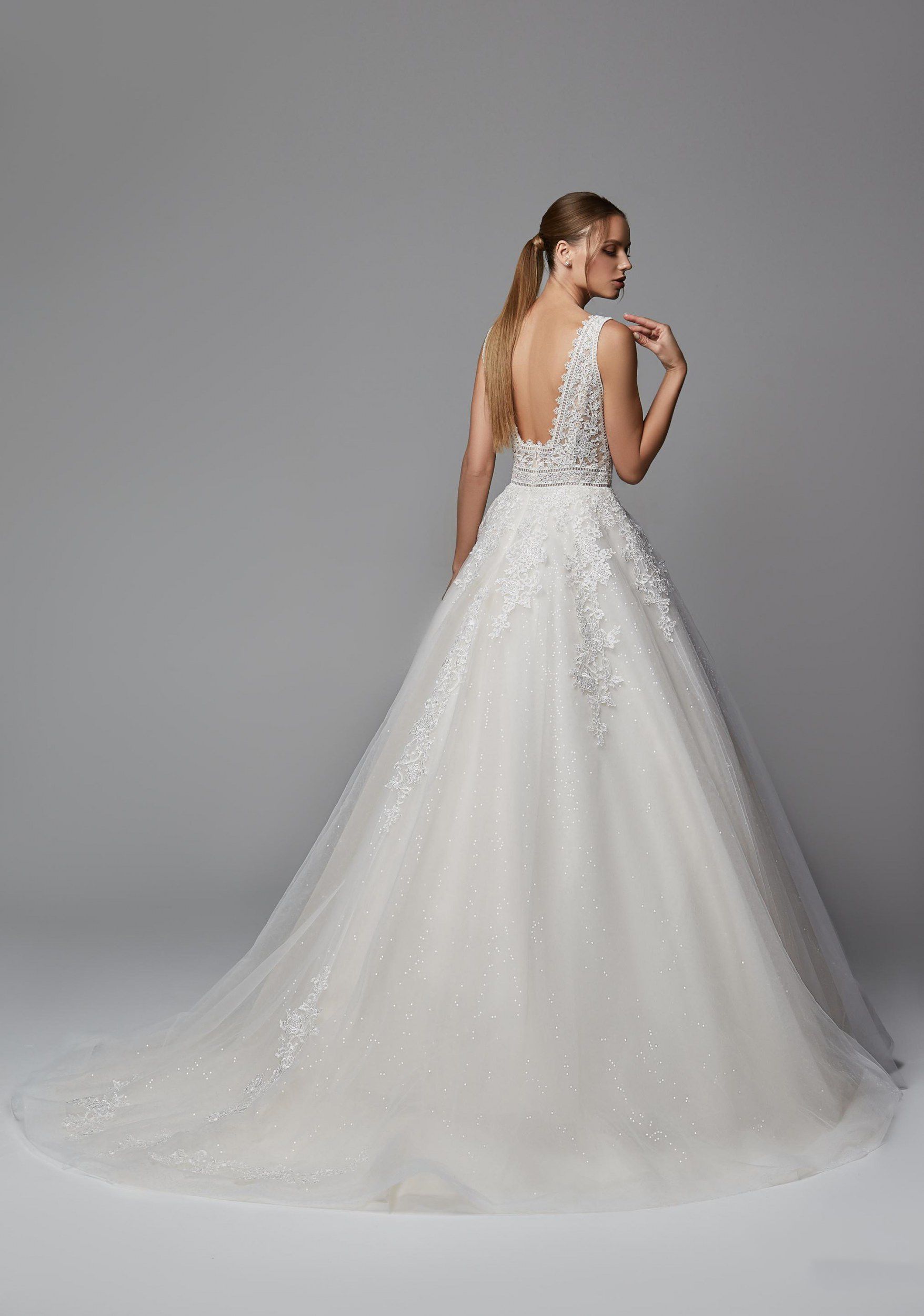 Eine Frau in einem weißen Hochzeitskleid steht vor einem weißen Gebäude.