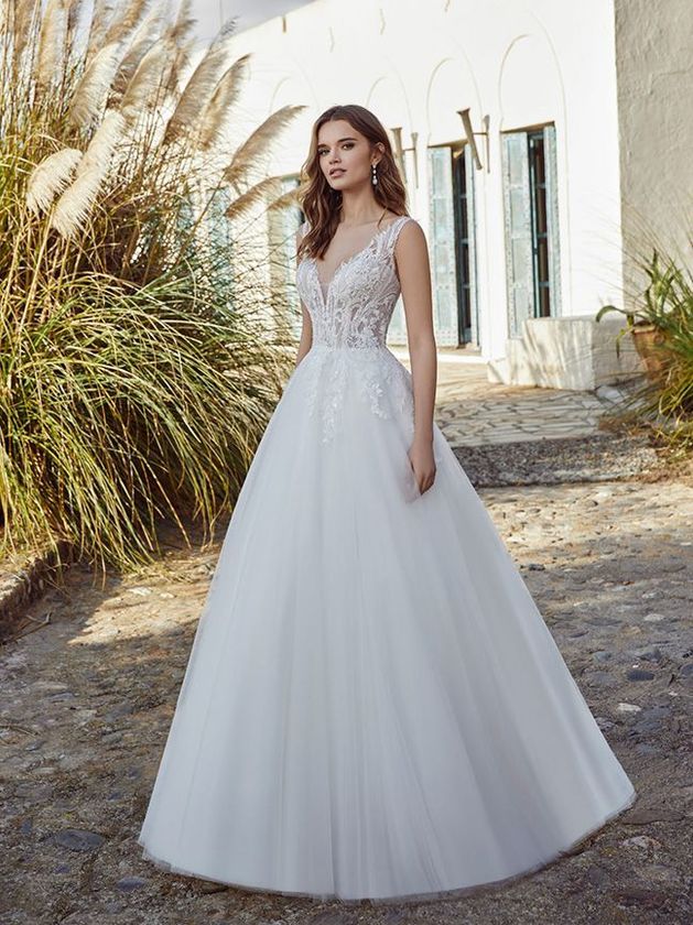 Eine Frau in einem weißen Brautkleid steht vor einem Gebäude.