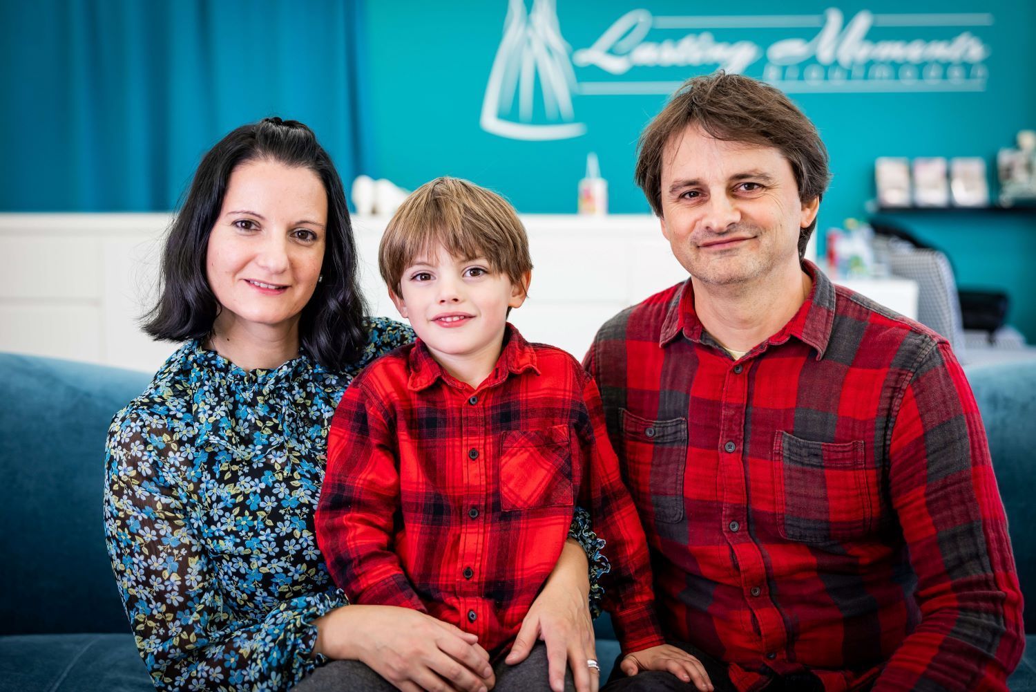 Eine Familie posiert auf einem Sofa sitzend für ein Foto.