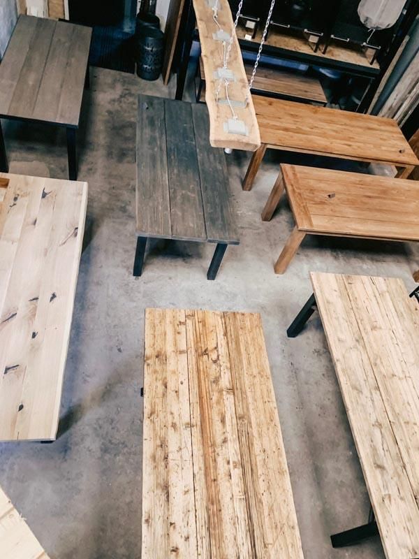 Auf einem Betonboden stehen mehrere Holztische und Bänke.