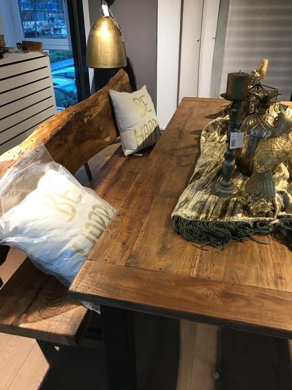 Ein Holztisch mit einer Bank und Kissen darauf.