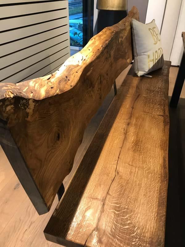 Eine Holzbank mit einem Kissen darauf, auf dem „Happy“ steht