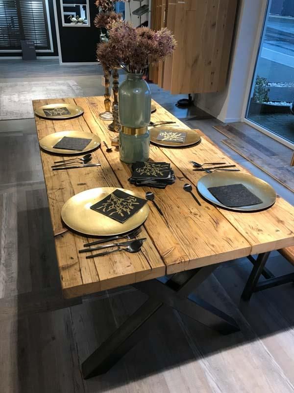 Ein Holztisch mit Tellern und Besteck darauf.