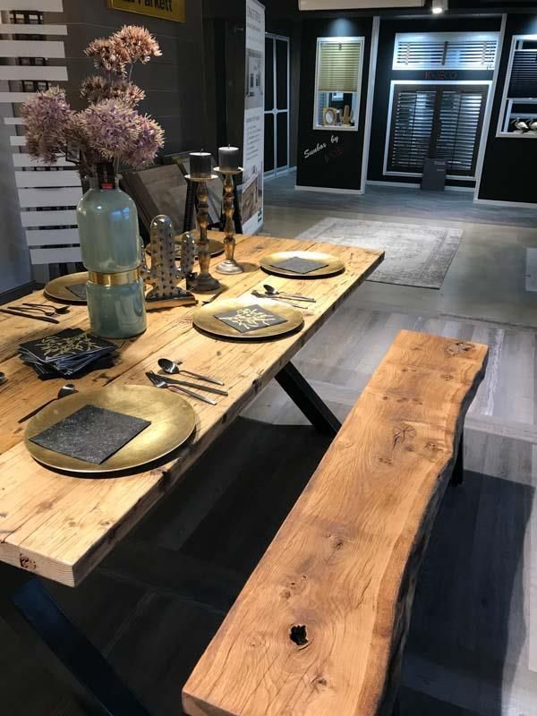 Ein Holztisch mit Tellern und Besteck darauf in einem Raum.