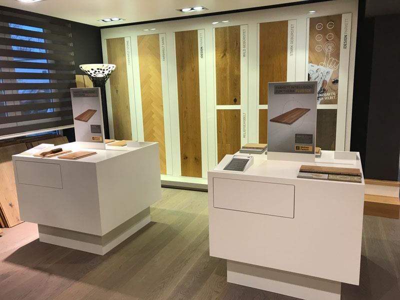 Ein Raum mit zwei weißen Tischen und einer Ausstellung von Holzböden